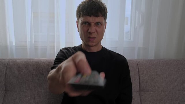 Man struggling with smart TV, streaming service or connected home device while using remote control, digital technology frustration