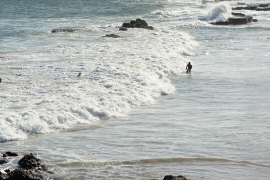 Bathers in the sea with waves and rocks