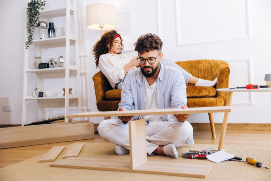 Young couple assembling flat pack furniture for new home