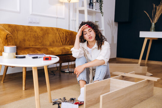 Woman feeling tired and frustrated assembling flat pack furniture at home