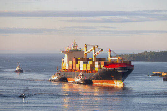 Bateau cargo avec conteneurs et bateaux accompagnateurs, jour, horizontal