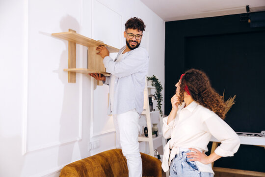 Couple collaborating on home renovation mounting wooden shelf
