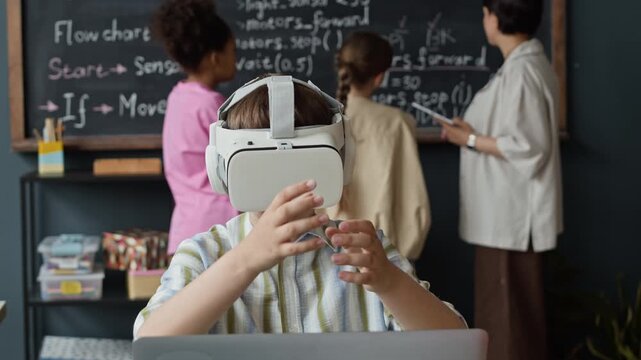 Caucasian child wearing VR headset gesturing with hands during STEM lesson in classroom. Perfect for promoting modern educational technology and virtual reality learning software