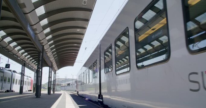 Commuters boarding a passenger train at a railway station platform.