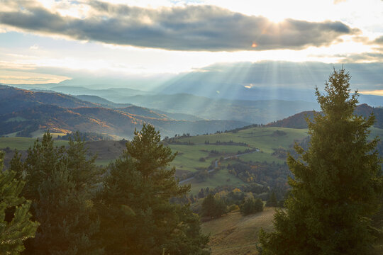 Dramatic sunbeams breaking through clouds over autumn mountain valley in Pieniny.