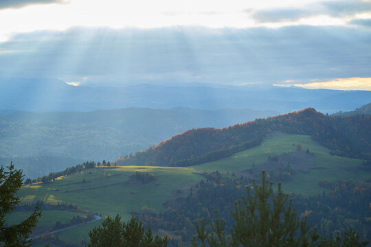 Sunbeams lighting up green mountain pastures during autumn sunset in Pieniny.