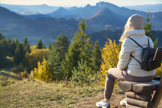 Female traveler sitting on a wooden bench and enjoying the view