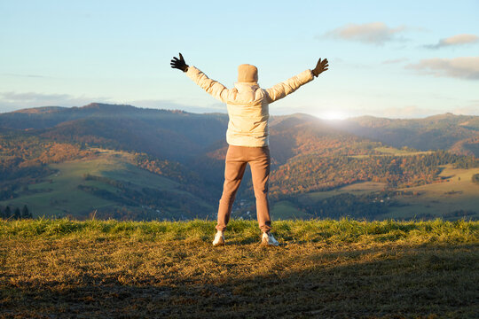 A person standing on hillside with open arms enjoying scenic aut