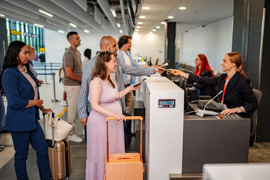 Passengers checking in luggage at airport counter, traveling for vacation
