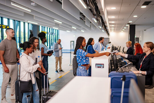 Passengers checking in at airport airline counter, handling documents