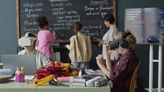 Multiethnic children wearing VR headsets and coding on blackboard during robotics class with teacher. Ideal for promoting STEM education and modern school technology