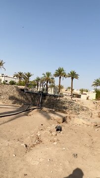 Stone ruins and a lush date palm oasis at the historic othman well.