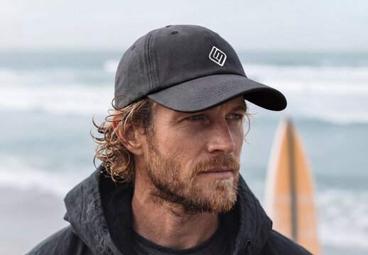 Man at the Ocean Wearing a Black Cap with Logo Mockup