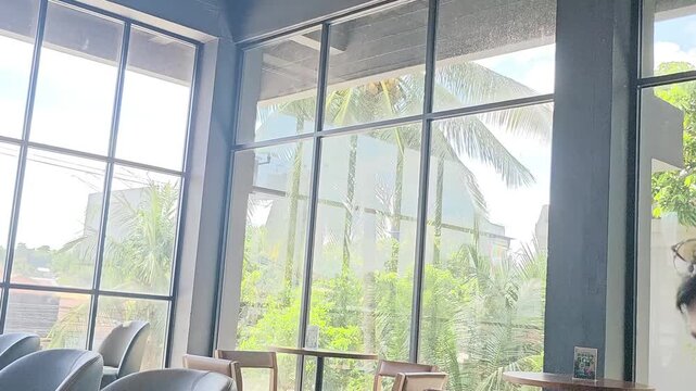 modern office building,Large windows frame lush greenery outside. Modern interior features minimalist furniture. Soft natural light bathes the space evenly. Calm atmosphere suggests peaceful 