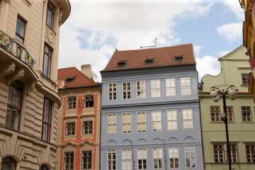 Row of pastel-colored historic townhouses with decorative facades and red tile roofs viewed from street level. Multi-story buildings feature tall sash windows © Alena