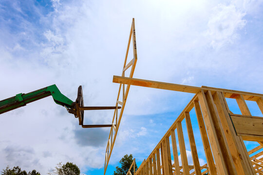 Construction workers use machine to lift wooden frame into place at building