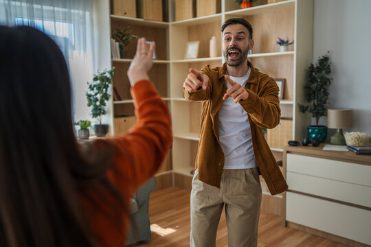Happy man playing charades with friends at home
