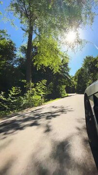 convertible car in sunny nature on a bright summer day. wide angle pursuit shot - vertical video for reels and story
