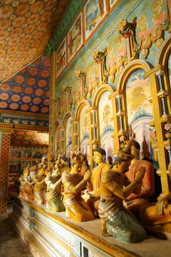 Row of traditional Buddha statues and worshipping disciple figures inside Wewurukannala Vihara.