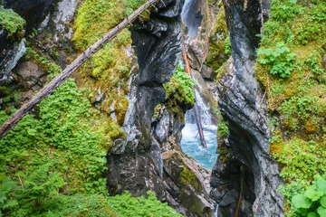 rauschender Wasserfall zwischen Felsen mit altem Baumstamm © by paul