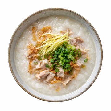 Chicken congee topped with shredded ginger, scallions, and crispy shallots in a rustic bowl isolated on white solid background