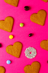 Fototapeta premium Top view of candies and heart shaped cookies on a vibrant pink background. Dessert photography, sweet treats.