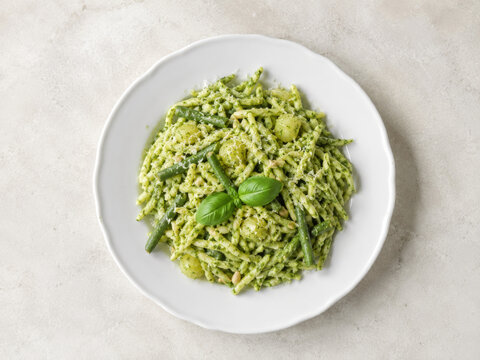 Plato de pasta con pesto y verduras servido en un plato blanco