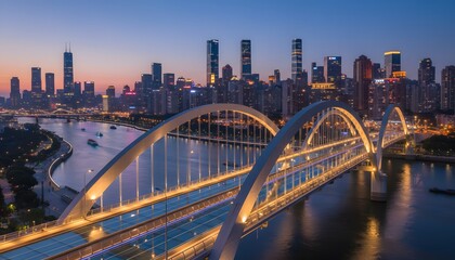 Fototapeta premium A large illuminated bridge over a river with a city skyline in the background at dusk.