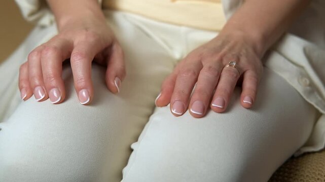 Woman's anxious hands. Close-up view of a woman's nervous hands with a beautiful french manicure and a diamond ring, fidgeting on her lap while she is anxiously waiting for an important moment
