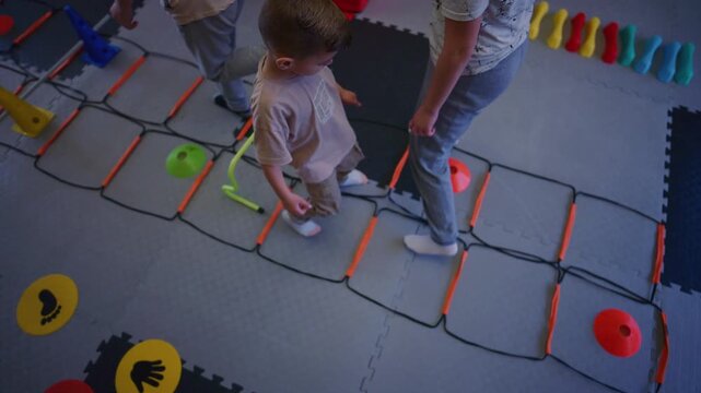 Young children participate in engaging fitness drills, utilizing an agility ladder and cones. Kids are actively playing and developing their physical skills in a structured environment.