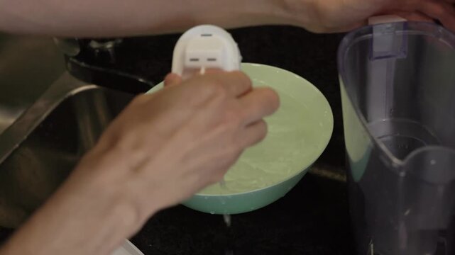 Changing water filter - Hands taking submerged water filter from bowl and placing into reusable water pitcher