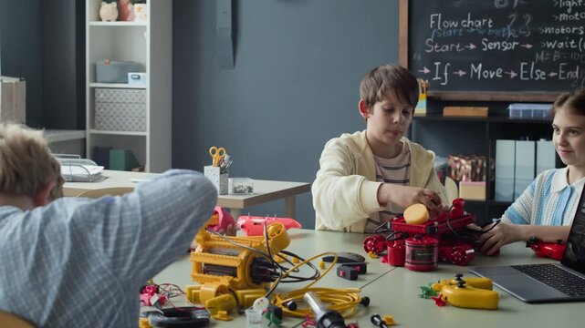 Multiethnic children assembling robotic toys and using laptop during STEM class. Footage is ideal for promoting elementary school science programs, modern education, and technology camps