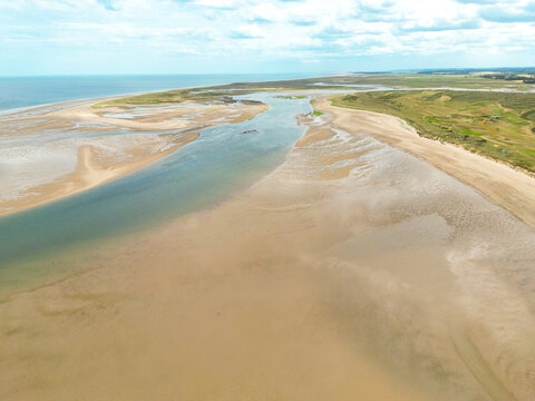 Interesting drone view of low tide at Brancaster beach on the North Norfolk coastline. Almost empty of beach goers, a WW2 shipwreck is located at the top left of the image on the sand bar.
