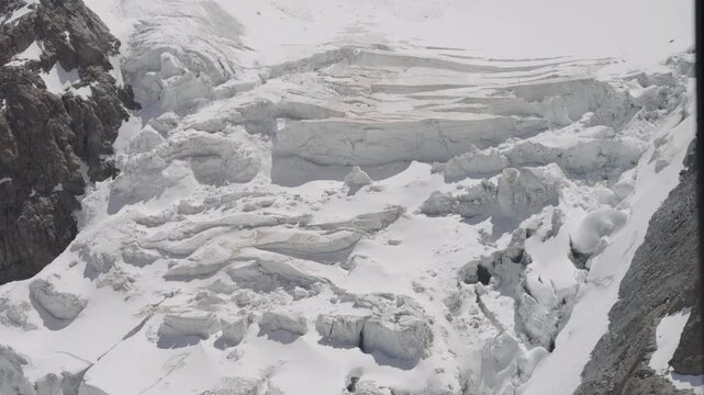 Large blocks of ice cracking and collapsing from a melting glacier on a steep mountain slope