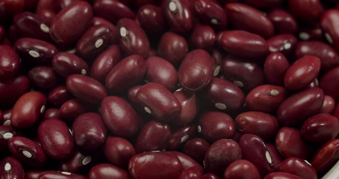 A close-up top view captures the nutritious legumes, highlighting a staple food for healthy eating. Red kidney beans spinning in a bowl on a white background