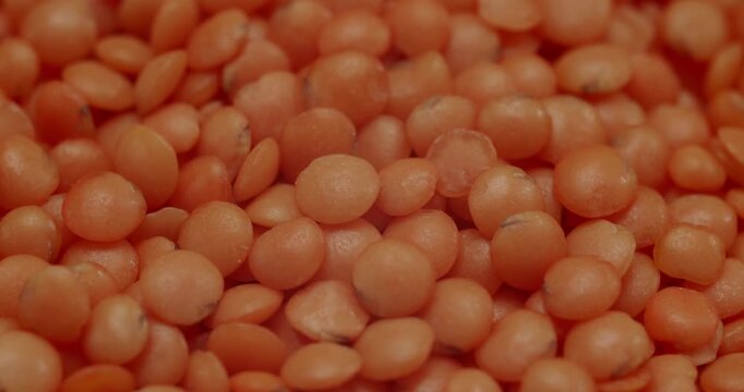 Red lentils falling in slow motion. Raw organic red lentils rotating. Healthy eating concept with a background of protein-rich legumes, ideal for vegan and vegetarian diets and cooking shows.