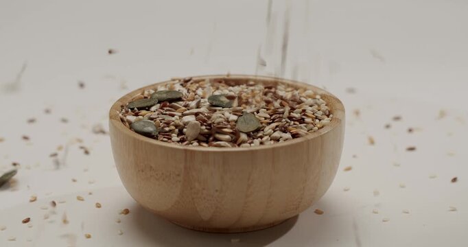 Extreme close-up of a mix of healthy organic seeds falling slowly, featuring sunflower, pumpkin, flax, and sesame seeds, creating a textured background for nutrition and diet concepts.