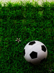 Fototapeta premium Soccer Ball on Artificial Turf: Overhead View of Classic Black and White Football on Vibrant Green Synthetic Field