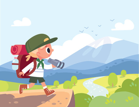 Young active boy scout wearing backpack, carrying binoculars walks along hiking route, trail through a lush green valley. Mountains rise in background. Bright blue sky, shining sun summer countryside