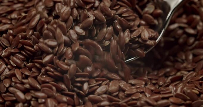 Macro view of natural brown flax seeds rotating in a wooden bowl on a white background, highlighting their texture and benefits for a healthy diet, vegetarian lifestyle, and superfood nutrition.