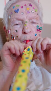 Playful senior woman blowing party horn noisemaker