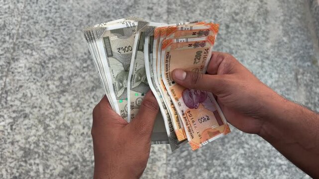 Close up shot of an Indian man counting cash outdoors, male hands holding and counting Indian currency cash, finance and investment concept