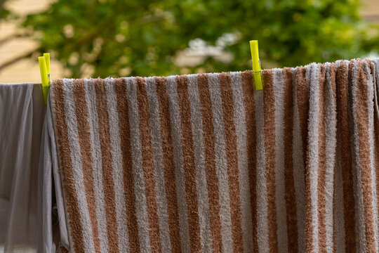 Brown and white striped towel drying on a clothesline outdoors