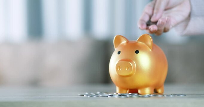 Hand putting a coin into a golden piggy bank, saving money, financial planning, investment, wealth, future savings, budgeting, and financial security, close-up