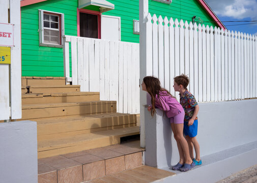 Kids peek around the edge of a picket fence