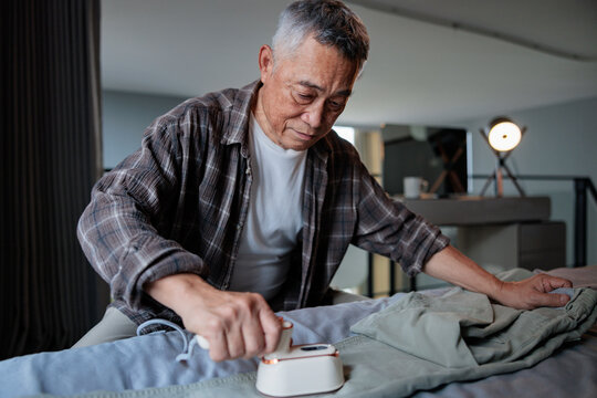 Man ironing clothes with a small iron.