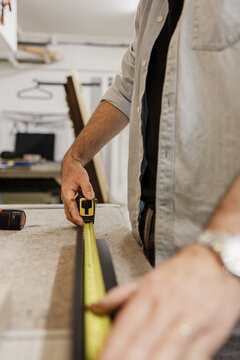 Craftsperson measuring with tape in workshop for precision work