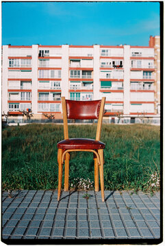 an old chair stands before apartment buildings, 35mm film
