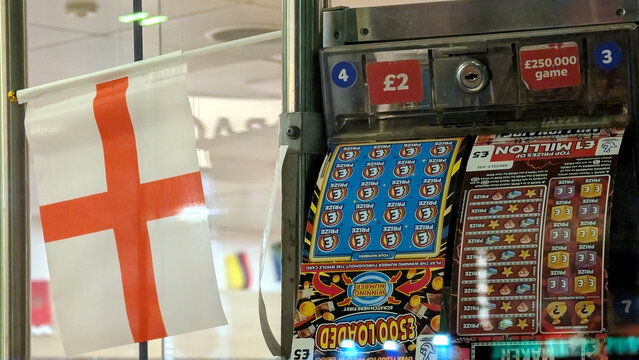 Leicester, England, UK - 20 June 2026: National lottery scratchcards in dispenser with England flag, gambling and lottery machine in UK, British scratch cards close up