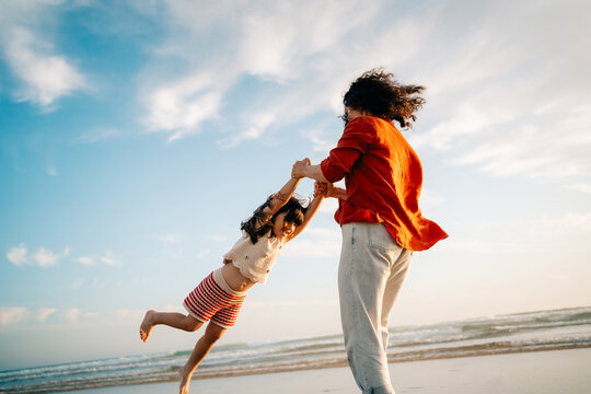 Child Plays at the Beach With Parent During Sunset